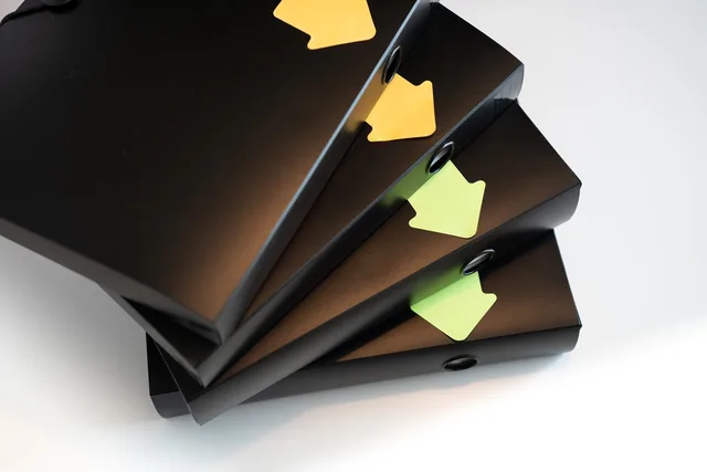 A stack of black ring binders with yellow and green labels for organization. Marketing automation data hygiene